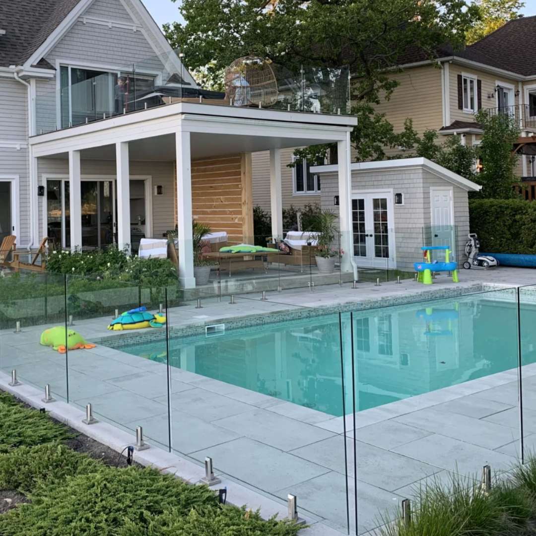 Frameless glass pool railing around a modern backyard pool