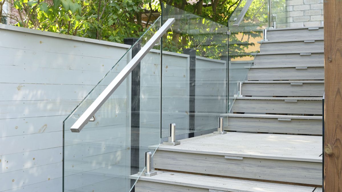 Custom frameless glass stair railing with stainless handrail on outdoor composite steps
