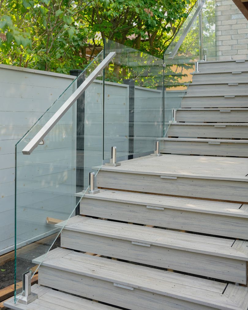 Frameless glass railing along an outdoor staircase with stainless handrail