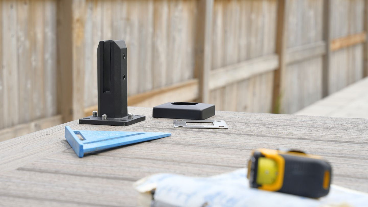 Black glass railing spigots, level and tape measure laid out on a composite deck