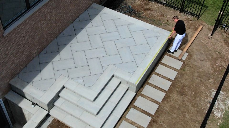 Installer measuring a deck area with a straightedge before glass railing installation
