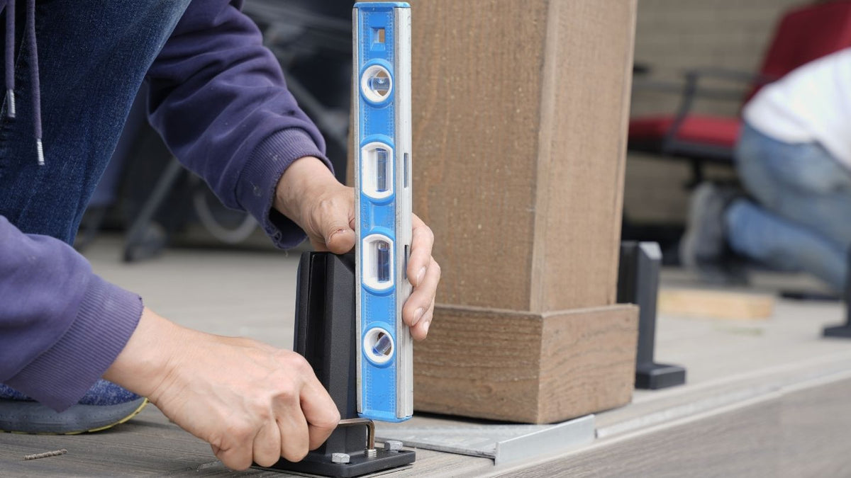 Installer checking a black railing post for plumb with a spirit level