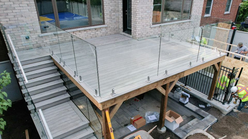 Frameless glass railing panels positioned in stainless spigots on a backyard deck